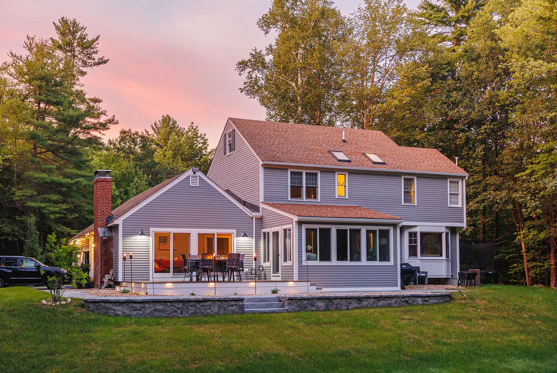 Photo of a home with a four-season room addition, along with a deck and fire table - Sunroom builder and enclosures contractor - Southern, New Hampshire