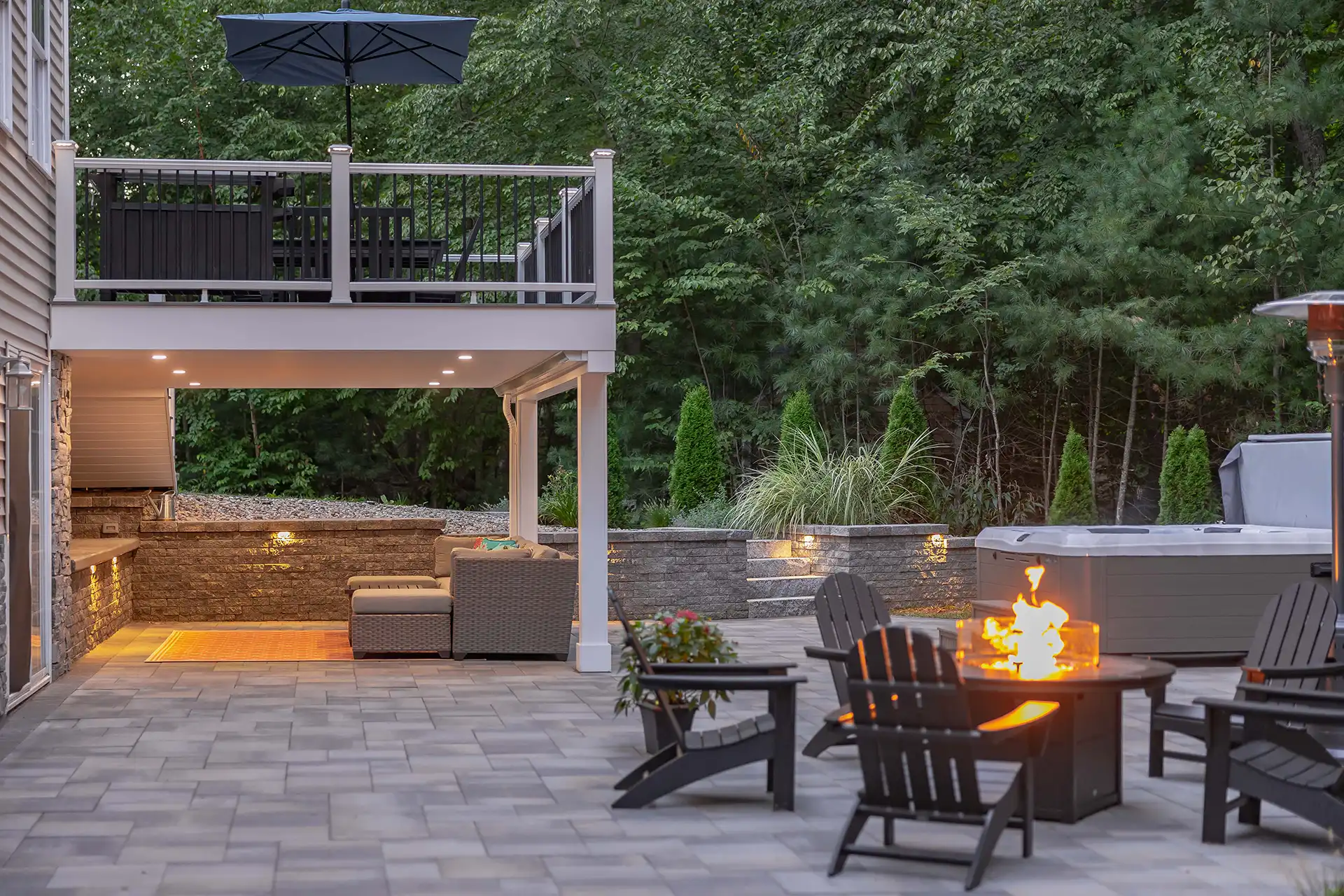 Photo of elevated deck, paver patio, with fire pit and outdoor furniture.