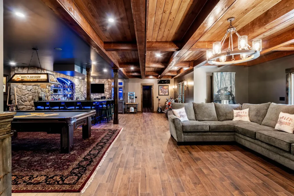 Wide view of remodeled basement with pool table bar and furniture