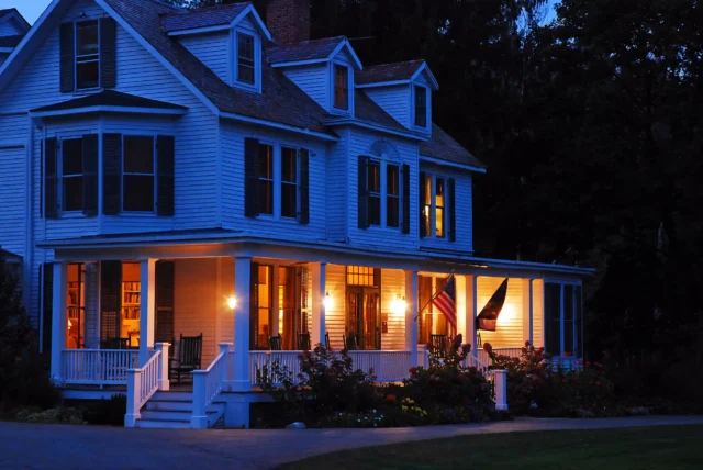 photo of a wraparound porch at night with lights illuminated - Porch builders near me in New Hampshire